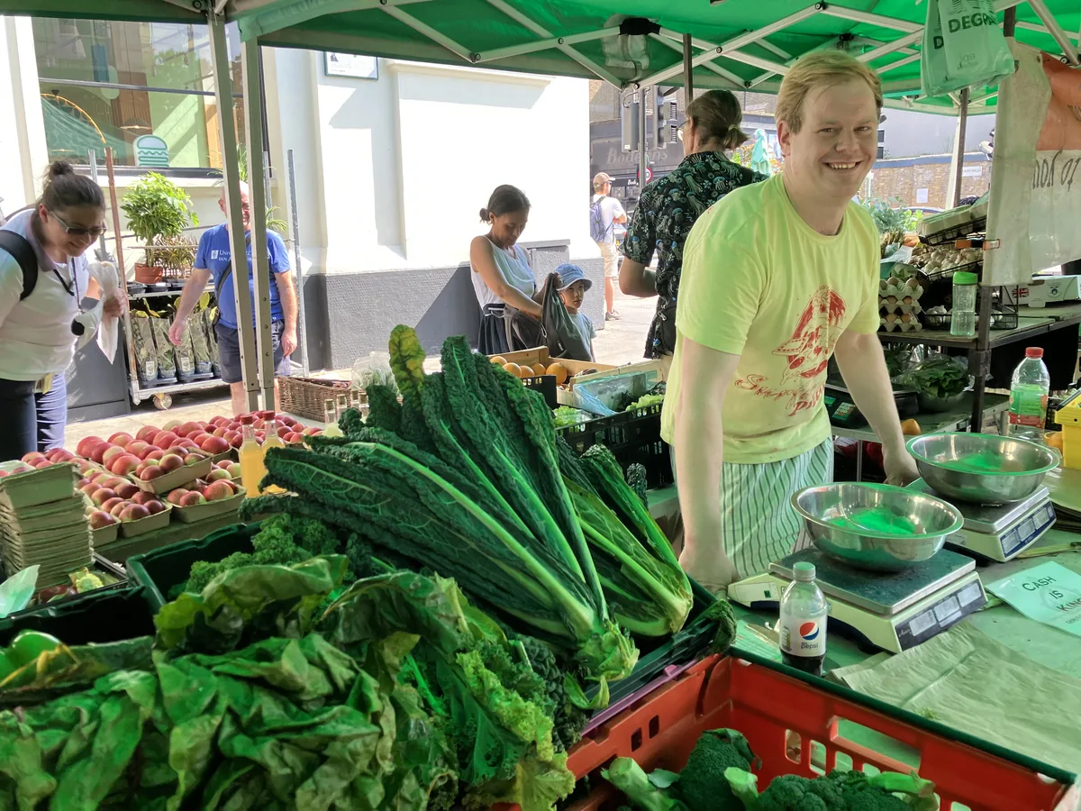 Fresh vegetable stall and trader at Venn Street Market in Clapham Old Town